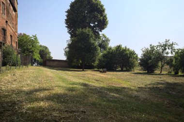 Terk edilmiş bir şatonun cephesi ve önünde de güneşli bir günde İtalya kırsalında bir çimen.