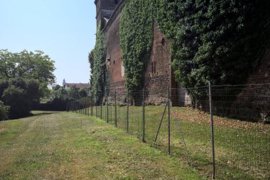 İtalya kırsalında güneşli bir günde ağaçlarla çevrili terk edilmiş bir kalenin yanındaki patikada.