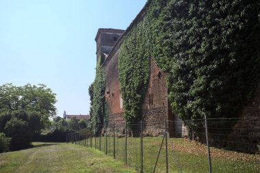 İtalya kırsalında güneşli bir günde ağaçlarla çevrili terk edilmiş bir kalenin yanındaki patikada.