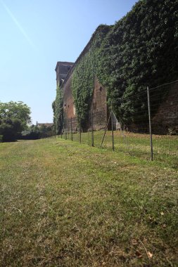 İtalya kırsalında güneşli bir günde ağaçlarla çevrili terk edilmiş bir kalenin yanındaki patikada.