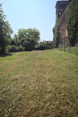 İtalya kırsalında güneşli bir günde ağaçlarla çevrili terk edilmiş bir kalenin yanındaki patikada.
