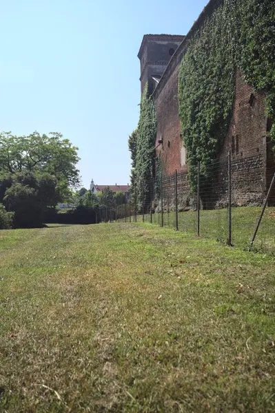 İtalya kırsalında güneşli bir günde ağaçlarla çevrili terk edilmiş bir kalenin yanındaki patikada.