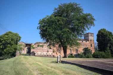 Kenarında kavak ağacı olan bir meydan ve arka planında ağaçlarla çevrili terk edilmiş bir saray İtalya kırsalında güneşli bir günde