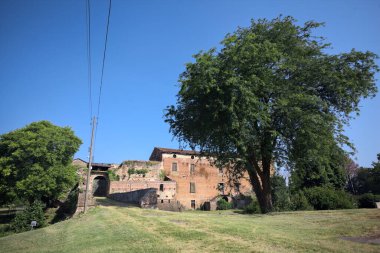 Kenarında kavak ağacı olan bir meydan ve arka planında ağaçlarla çevrili terk edilmiş bir saray İtalya kırsalında güneşli bir günde