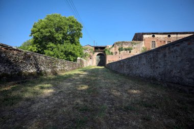 Güneşli bir günde, İtalya 'da terk edilmiş bir sarayın kapısındaki ahşap kapıya uzanan çimlerle kaplı tuğla köprü.