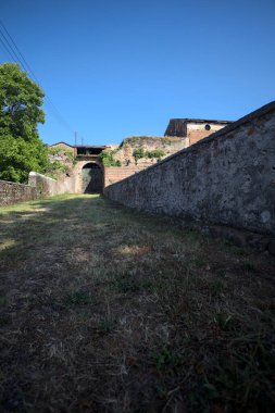 Güneşli bir günde, İtalya 'da terk edilmiş bir sarayın kapısındaki ahşap kapıya uzanan çimlerle kaplı tuğla köprü.