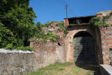Güneşli bir günde, İtalya 'da terk edilmiş bir sarayın kapısındaki ahşap kapıya uzanan çimlerle kaplı tuğla köprü.