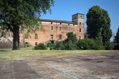 Kenarında kavak ağacı olan bir meydan ve arka planında ağaçlarla çevrili terk edilmiş bir saray İtalya kırsalında güneşli bir günde