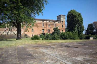 Kenarında kavak ağacı olan bir meydan ve arka planında ağaçlarla çevrili terk edilmiş bir saray İtalya kırsalında güneşli bir günde