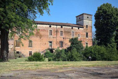 Kenarında kavak ağacı olan bir meydan ve arka planında ağaçlarla çevrili terk edilmiş bir saray İtalya kırsalında güneşli bir günde