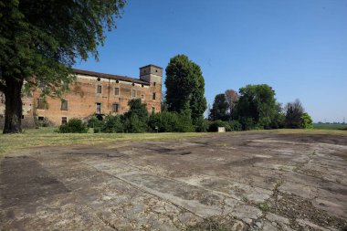 Kenarında kavak ağacı olan bir meydan ve arka planında ağaçlarla çevrili terk edilmiş bir saray İtalya kırsalında güneşli bir günde