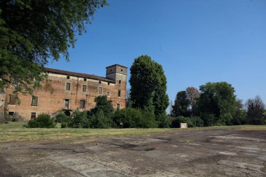 Kenarında kavak ağacı olan bir meydan ve arka planında ağaçlarla çevrili terk edilmiş bir saray İtalya kırsalında güneşli bir günde