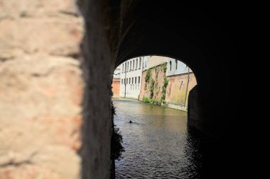Güneşli bir günde, bir İtalyan kasabasının ortasında, bir köprünün kemerlerinin altından geçen su akıntısı.