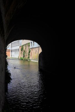 Güneşli bir günde, bir İtalyan kasabasının ortasında, bir köprünün kemerlerinin altından geçen su akıntısı.