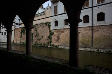 Gölgede sütunlar, İtalyan kasabasının duvarlarıyla çevrili bir su deresinin yanında kemerler.