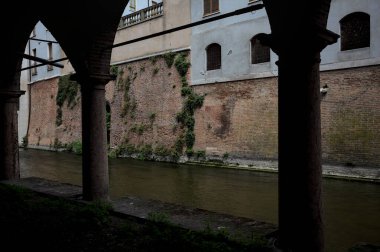 Gölgede sütunlar, İtalyan kasabasının duvarlarıyla çevrili bir su deresinin yanında kemerler.