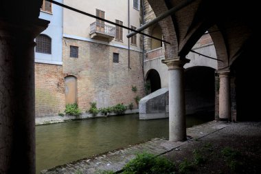 Gölgede sütunlar, İtalyan kasabasının duvarlarıyla çevrili bir su deresinin yanında kemerler.