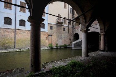 Gölgede sütunlar, İtalyan kasabasının duvarlarıyla çevrili bir su deresinin yanında kemerler.