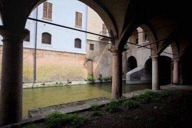 Gölgede sütunlar, İtalyan kasabasının duvarlarıyla çevrili bir su deresinin yanında kemerler.