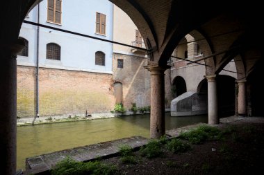 Gölgede sütunlar, İtalyan kasabasının duvarlarıyla çevrili bir su deresinin yanında kemerler.