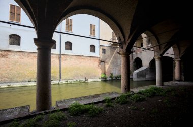 Gölgede sütunlar, İtalyan kasabasının duvarlarıyla çevrili bir su deresinin yanında kemerler.