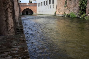 Bir İtalyan kasabasında yüksek binaların arasından geçen su akıntısı
