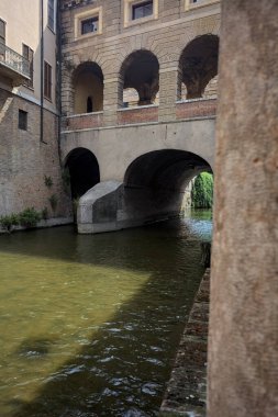 Bir İtalyan kasabasında dar bir su akıntısı üzerinde kemerli tuğla köprü
