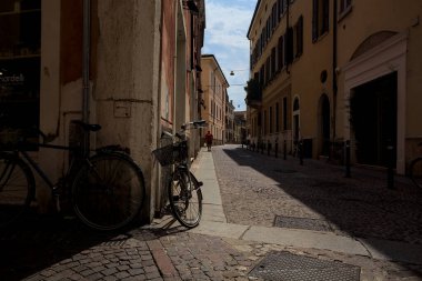 Güneşli bir günde İtalya 'da bir binanın köşesine parketmiş bisikletli dar kaldırımlı cadde.