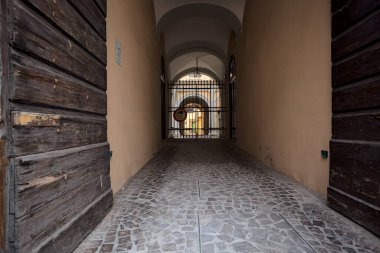 Bir İtalyan kasabasında demir bir kapı tarafından kapatılmış tarihi bir binanın kemer girişi.