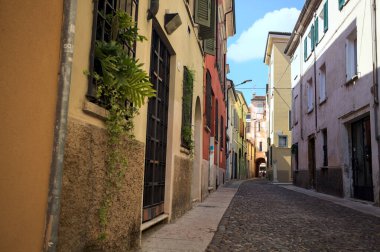 Güneşli bir günde, İtalya 'nın bir şehrinde, bir binanın altında kapalı bir geçide açılan gölgedeki kaldırımlı cadde.