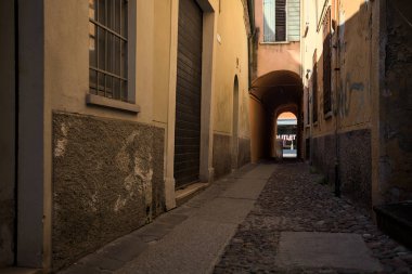 Güneşli bir günde, İtalya 'nın bir şehrinde, bir binanın altında kapalı bir geçide açılan gölgedeki kaldırımlı cadde.