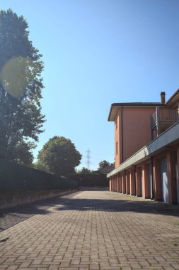 Çitlerle çevrili bir evin arka bahçesi. Arka tarafında kapalı garaj kapıları var. Güneş ışığı var.