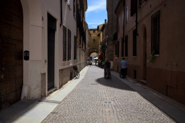 Bir İtalyan kasabasında dar bir sokak, yarı gölgede kemerli bir yol.