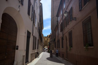 Bir İtalyan kasabasında dar bir sokak, yarı gölgede kemerli bir yol.