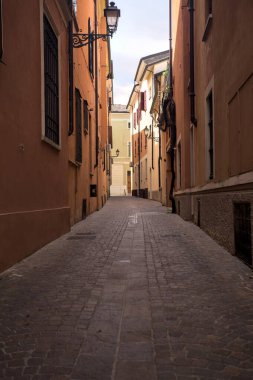 Üzerinde açık bir gökyüzü olan gölgede dar dar bir ara sokak.