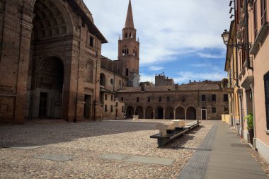 Mantova, İtalya - 27 Temmuz 2025 - Güneşli bir günde San Andrea Bazilikası 'nın bir tarafında çan kulesi ve bitişik binası ile kaldırımlı meydan