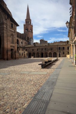 Mantova, İtalya - 27 Temmuz 2025 - Güneşli bir günde San Andrea Bazilikası 'nın bir tarafında çan kulesi ve bitişik binası ile kaldırımlı meydan