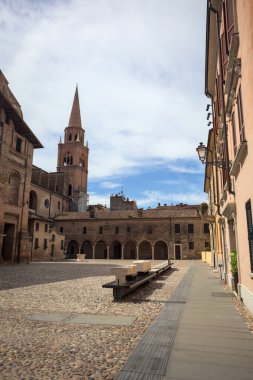 Mantova, İtalya - 27 Temmuz 2025 - Güneşli bir günde San Andrea Bazilikası 'nın bir tarafında çan kulesi ve bitişik binası ile kaldırımlı meydan