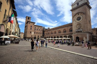 Mantova, İtalya - 27 Temmuz 2025 - Güneşli bir günde İtalya 'da bir meydanın kenarında saat kulesi olan bir saray