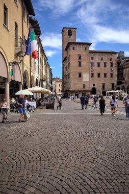 Mantova, İtalya - 27 Temmuz 2025 - Güneşli bir günde İtalya 'da bir meydanın kenarında saat kulesi olan bir saray