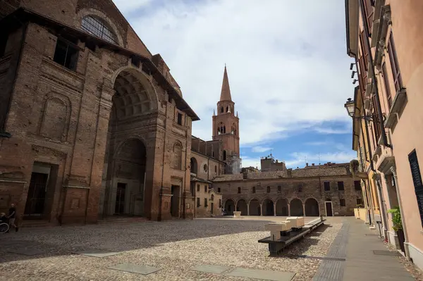 Mantova, İtalya - 27 Temmuz 2025 - Güneşli bir günde San Andrea Bazilikası 'nın bir tarafında çan kulesi ve bitişik binası ile kaldırımlı meydan