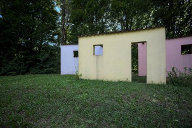 Parktaki bir grup ağacın arkasındaki ev cephesi şeklinde sanatsal kurulum