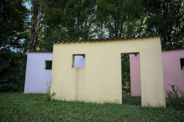 Parktaki bir grup ağacın arkasındaki ev cephesi şeklinde sanatsal kurulum