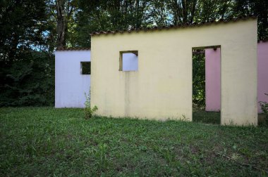 Parktaki bir grup ağacın arkasındaki ev cephesi şeklinde sanatsal kurulum