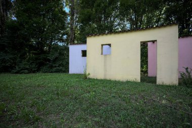 Parktaki bir grup ağacın arkasındaki ev cephesi şeklinde sanatsal kurulum