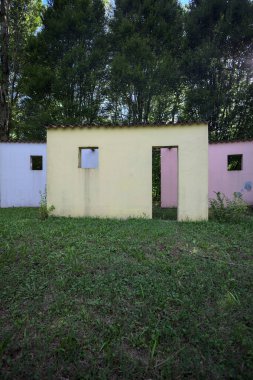 Parktaki bir grup ağacın arkasındaki ev cephesi şeklinde sanatsal kurulum