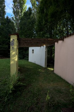 Parktaki bir grup ağacın arkasındaki ev cephesi şeklinde sanatsal kurulum