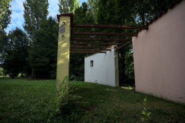 Parktaki bir grup ağacın arkasındaki ev cephesi şeklinde sanatsal kurulum