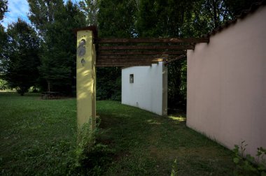 Parktaki bir grup ağacın arkasındaki ev cephesi şeklinde sanatsal kurulum