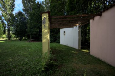 Parktaki bir grup ağacın arkasındaki ev cephesi şeklinde sanatsal kurulum